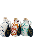 A collection of short white ceramics containing Golden Nectar, Organic, Extra Virgin, Olive Oil. One is speckled with dark blue paint, one speckled with orange paint and one with turquoise paint