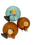 A collection of round, painted ceramic containers, of various colours, containing olive oil