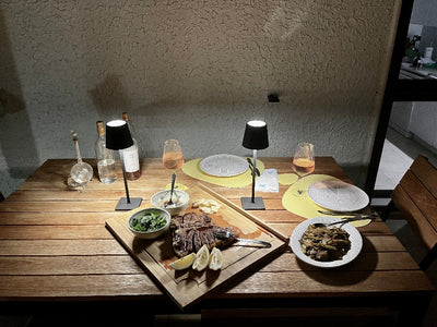 Dining table setup with plates, glasses, and food on a wooden surface.