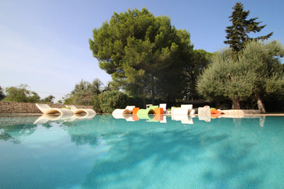 Pool with colorful lounge chairs surrounded by trees on a sunny day